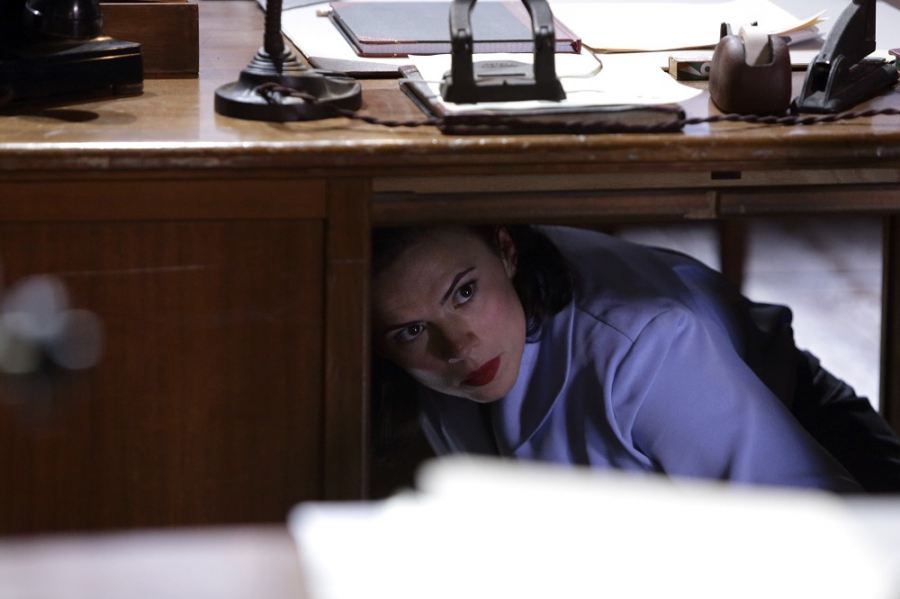 Peggy Carter (Hayley Atwell) se cache sous un bureau